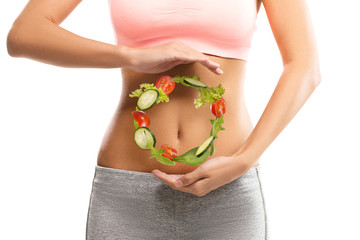 Fit, young woman holding a circle made out of vegetables over her abdomen 