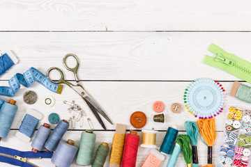 Tools and accessories for sewing on light wooden background. - obrazy, fototapety, plakaty