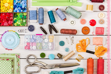 Tools and accessories for sewing on light wooden background.