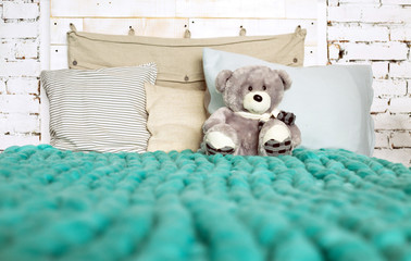 Merino wool blanket on bed with pillows in pastel colors and Ted