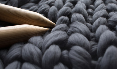 wooden knitting needles on background of grey merino wool blanke