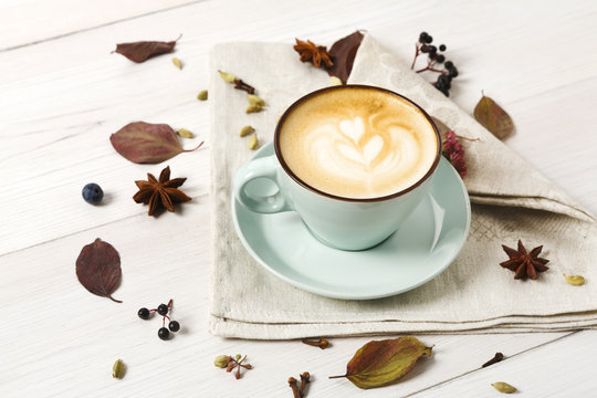 Autumn cappuccino coffee cup on white wood background