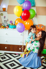 Brunette woman holds her child sitting before the sweet buffet