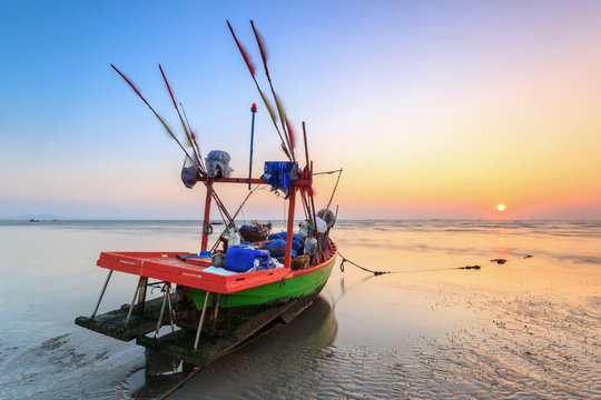 fishing boat on the beach with sunset