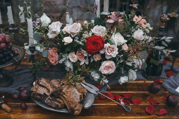 grilled meat lies on vintage plate served on a wooden table with candles in the background of a beautiful bouquet