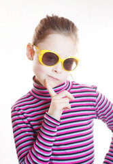 Coquettish little girl wearing striped blouse and sunglasses against white background