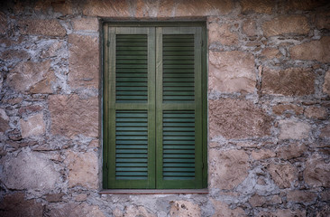 Fototapeta na wymiar Old green window with closed shutters