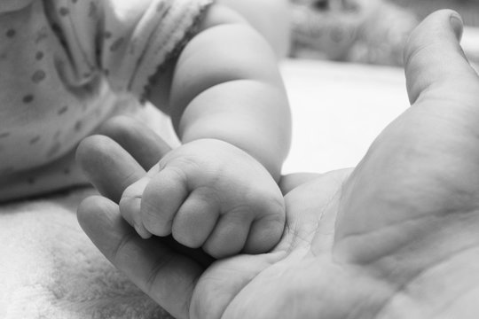 small child's hand in hand of adult parent closeup / black and white photo in retro style
