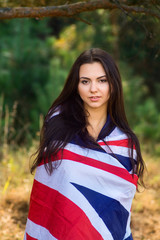 Young beautiful brunette girl posing with a British flag in autumn park