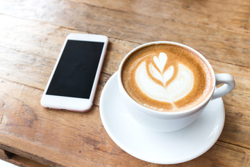 Cup of coffee and smart phone on wooden table
