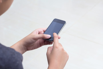 Woman with modern mobile phone in hands touching on a blank scre