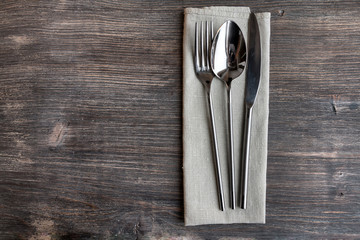 Concept of simple organic food - laconic design cutlery set on rustic wooden table and linen tissue. Top view. - obrazy, fototapety, plakaty