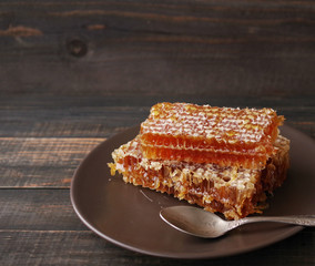  Honey in honeycombs on a brown plate on a wooden surface of a table