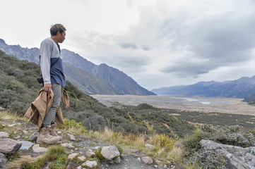 Fototapeta premium A man looking at the Tasman River from viewpoint along the walking trail to the Blue Lakes and Tasman Glacier View in Aoraki / Mount Cook National Park
