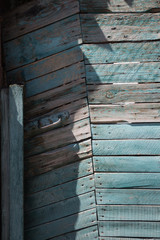 Blue painted peel off faded wooden door made of boards and nails with metal handle