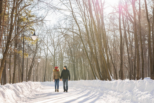 happy couple walking through a snowy forest in winter