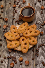 Small cups of coffee, cookies, cocoa beans and hazelnuts on wooden background