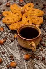 Small cups of coffee, cookies, cocoa beans and hazelnuts on wooden background