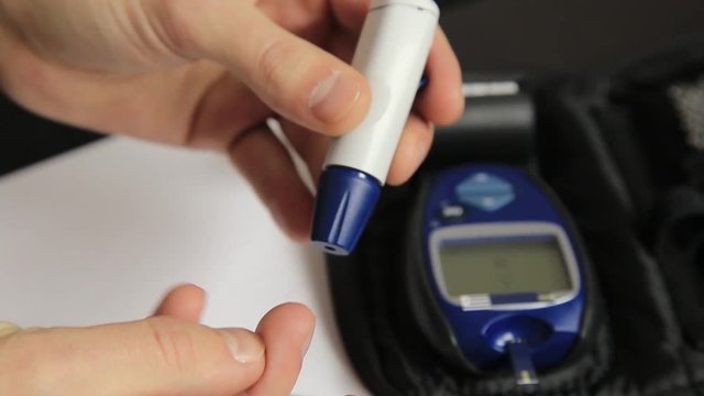 Measuring glucose level blood test using ultra mini glucometer and small drop of blood from finger and test strips. Dependent first type diabetes patient.