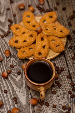 Small cups of coffee, cookies, cocoa beans and hazelnuts on wooden background