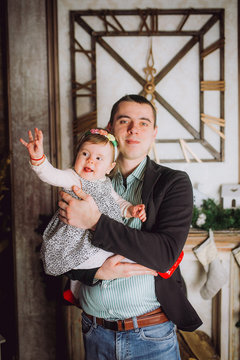 Portrait of happy father and adorable baby against domestic festive backdrop with Christmas tree.