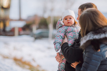 parenthood, fashion, season and people concept - happy family with baby in winter clothes outdoors