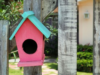 Old bird house or nest box hangs on the wooden fence.