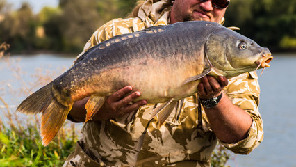 Happy angler with carp fishing trophy