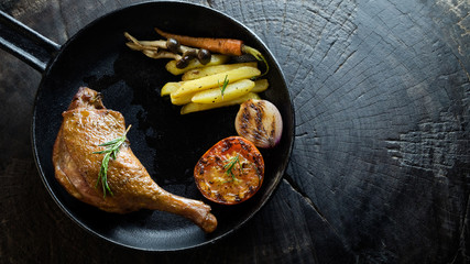 Grilled chicken with side dish in iron pan on wooden background