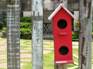 Old bird house or nest box hangs on the wooden fence.