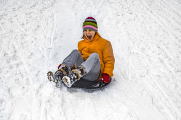 Fototapeta na wymiar girl has fun sledging down the snowy hill