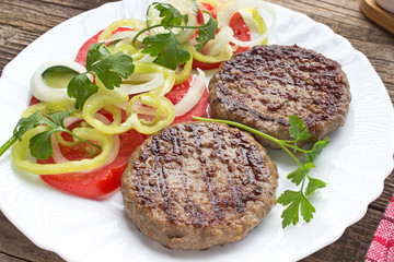 Grilled hamburger in plate with vegetable salad