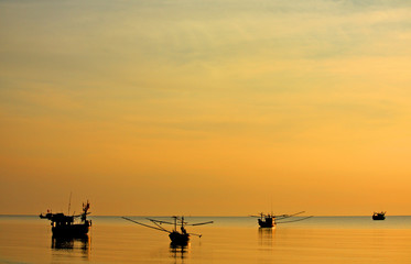 Backlit fishing boats on ocean horizon