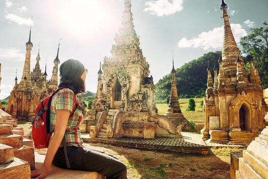 Traveller with backpack resting and looks at Buddhist stupas.