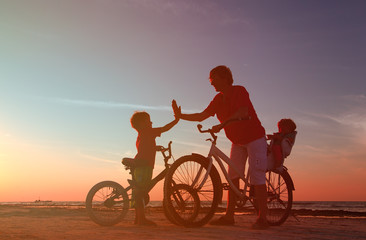 Fototapeta na wymiar Biker family silhouette, father with two kids on bikes
