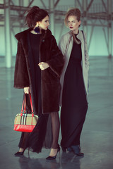 Two models at airport are waiting  private airplane. fashion look, stylish make up, perfect hairdo and interesting individual bags