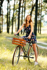 Fototapeta na wymiar Happy girl on a bicycle with a basket in the woods.