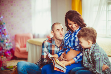 Funny man looks at his pregnant woman while she reads a book wit