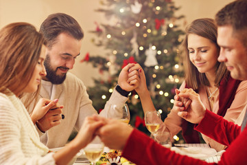 Group of friends praying over Christmas table
