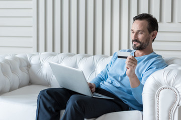 Confident delighted man using a credit card