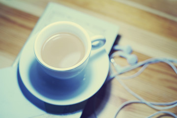 Cup of coffee, book and earphones on the table, top view