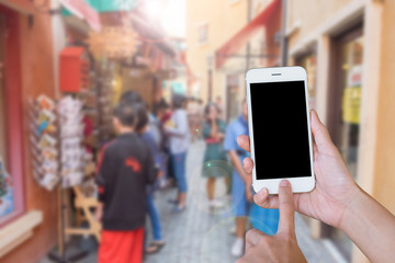 Hands woman are holding touch screen smart phone,tablet on blurred people shopping on street markets old building style background.