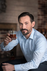 Nice happy man holding up his hand with a glass