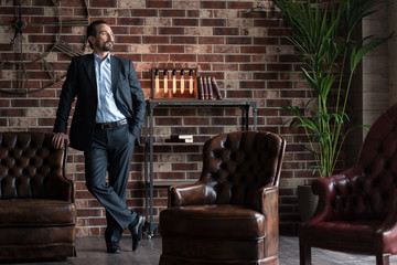 Handsome successful businessman standing in his study room
