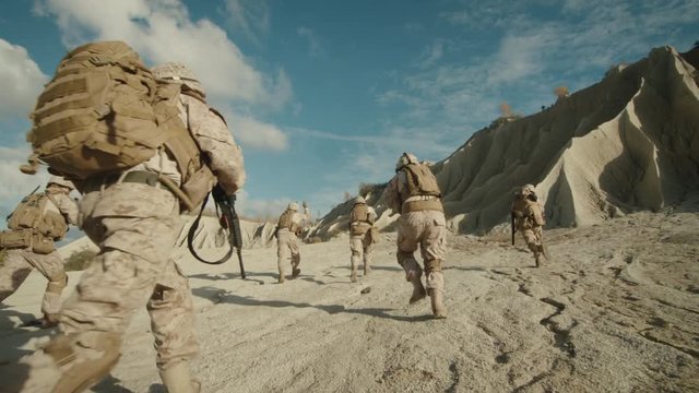  Follow Shot of Squad of Soldiers Running Forward During Military Operation in the Desert.  on RED EPIC Cinema Camera in 4K (UHD).