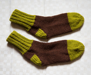 Pair of warm woolen colorful knitted socks on a linen background