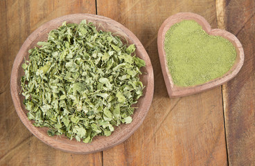 Moringa leaves and dust on the wooden background