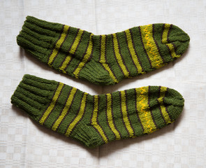 Pair of warm woolen colorful knitted socks on a linen background