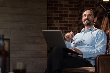 Cheerful self employed man holding his glasses