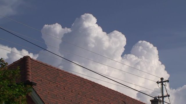 Gewitterwolken t&uuml;rmen sich bedrohlich am Himmel hinter dem Hausdach auf (Zeitraffer)